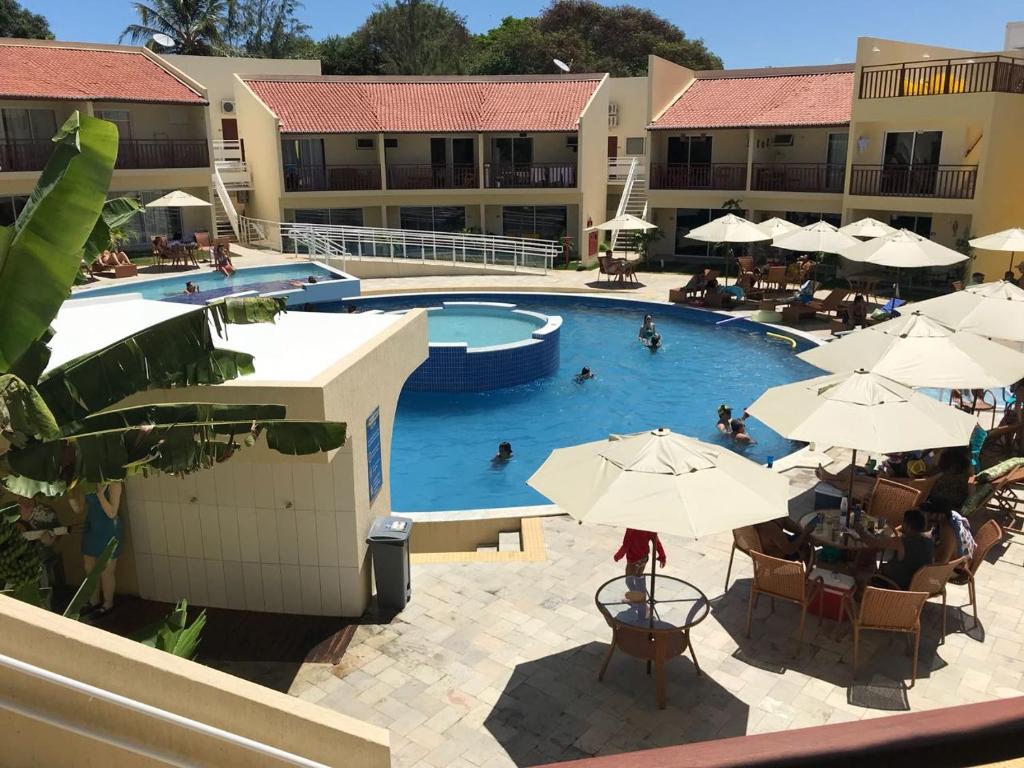 a swimming pool with umbrellas and people in a resort at Pipa Solar Água Flat Master Luxo - 2 Quartos com Ar Condicionados Independente Apto 252 in Pipa