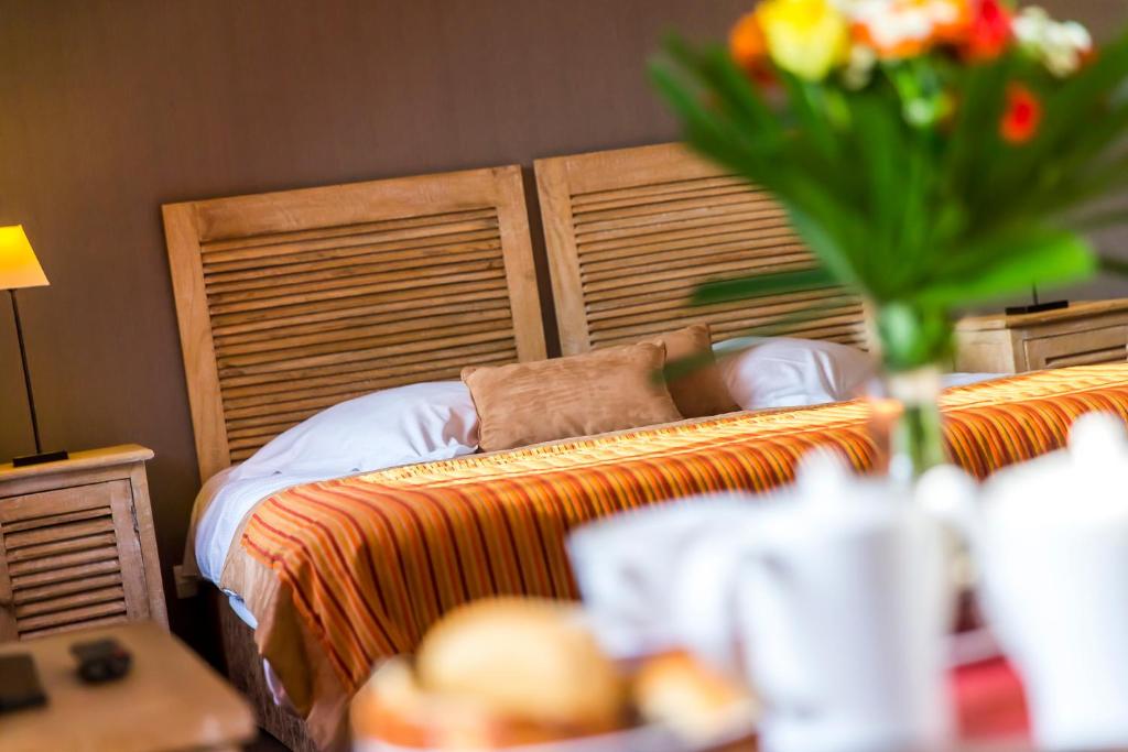 a bedroom with a bed with a vase of flowers at Almoria Hôtel & SPA in Deauville