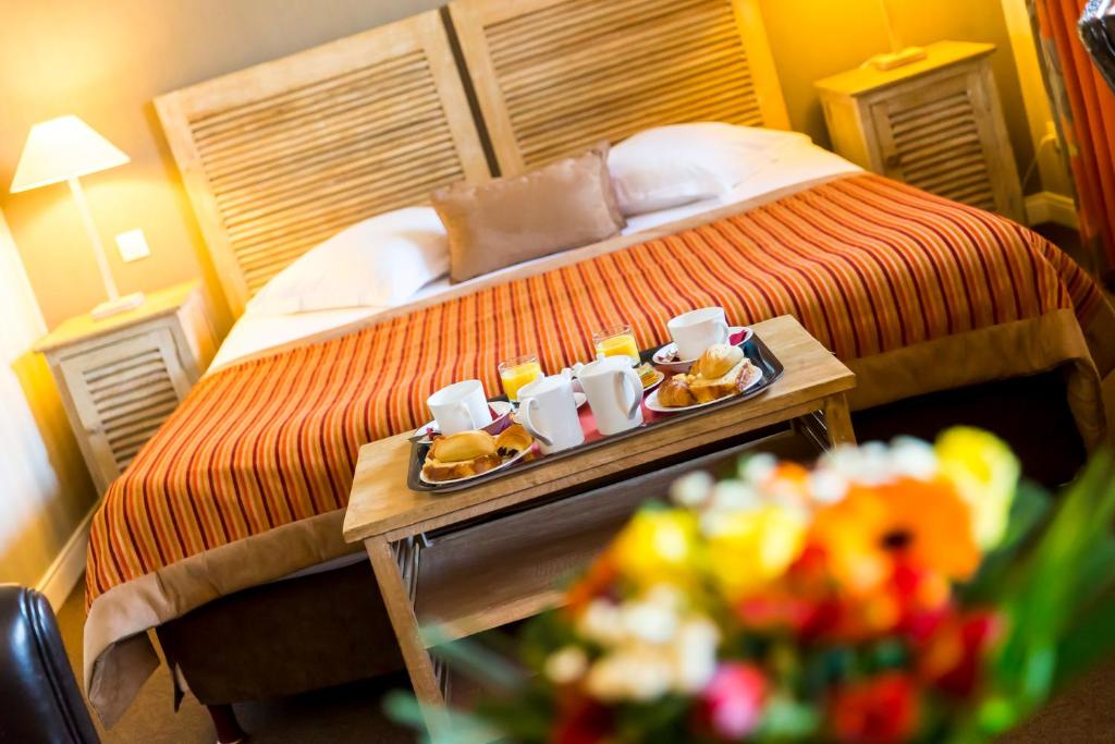 a hotel room with a bed with a tray of food on a table at Almoria Hôtel & SPA in Deauville