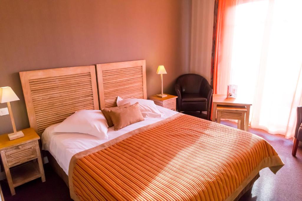 a bedroom with a large bed and a chair at Almoria Hôtel & SPA in Deauville