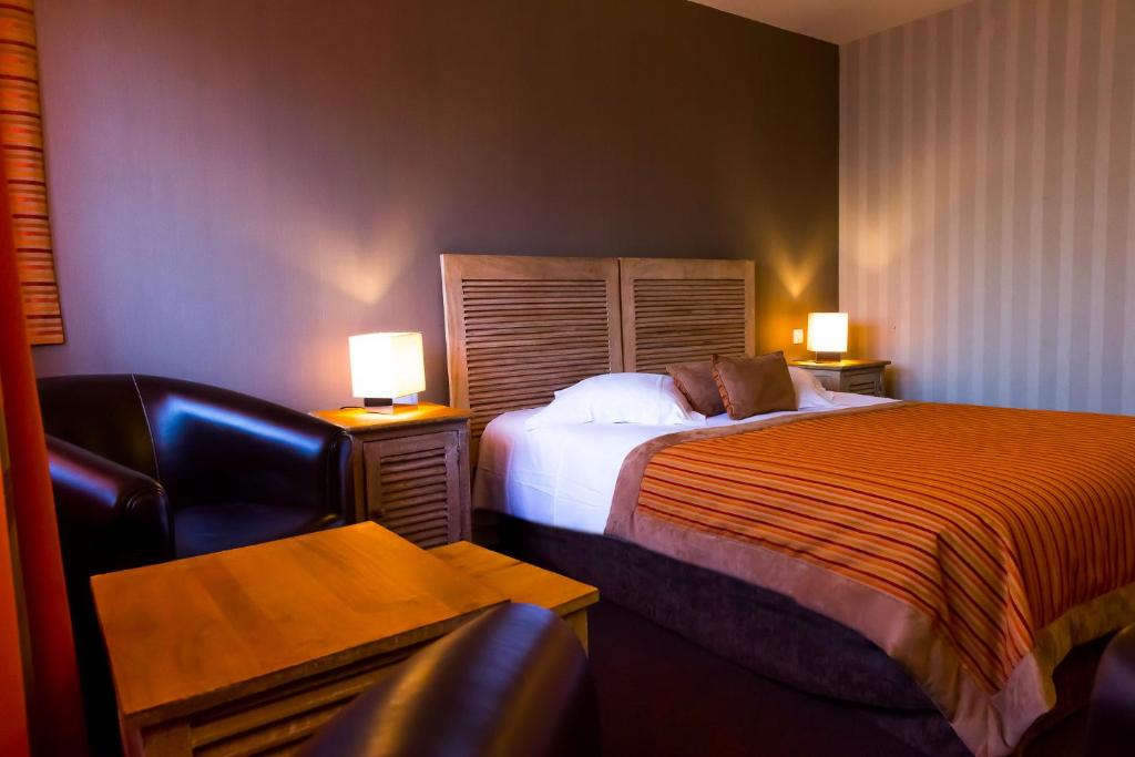 a hotel room with two beds and a chair at Almoria Hôtel & SPA in Deauville