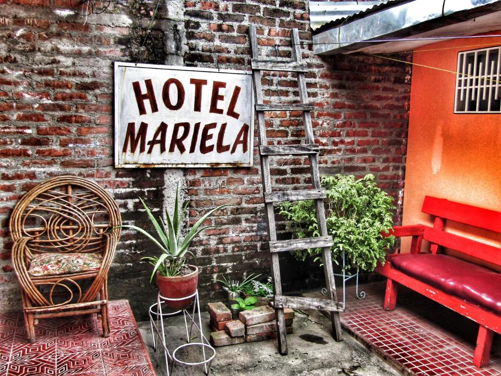 een bord voor een hotelmarkt naast een bakstenen muur bij Hostal Mariella in Estelí