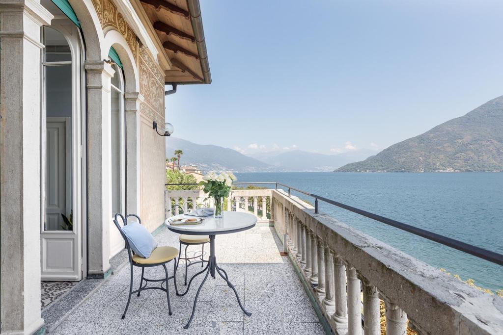 uma varanda com uma mesa e cadeiras com vista para a água em Villa Maria Hotel em Cannobio