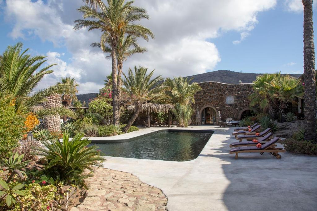 a swimming pool with lounge chairs and palm trees at Don Mario Resort in Pantelleria