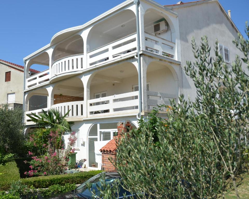 a white house with a balcony on the side of it at Apartmani Admiral in Novalja