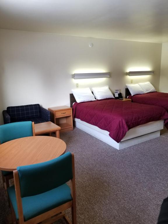 Habitación de hotel con 2 camas, mesa y sillas en Home Motel Abbotsford, en Abbotsford