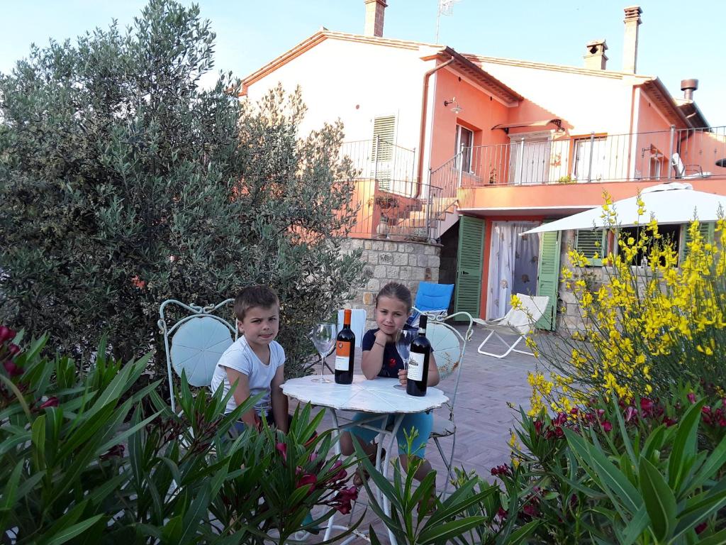 dos chicos sentados en una mesa con botellas de vino en Villa Rossana, en Sassofortino