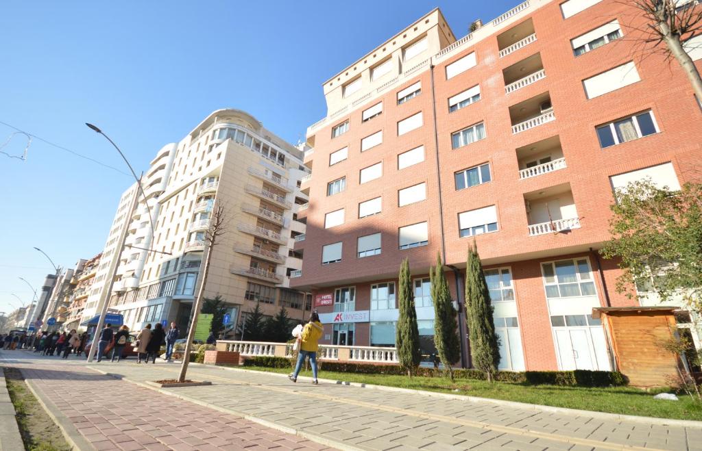 un grupo de personas caminando por una calle al lado de los edificios en Hotel Oresti Center, en Tirana