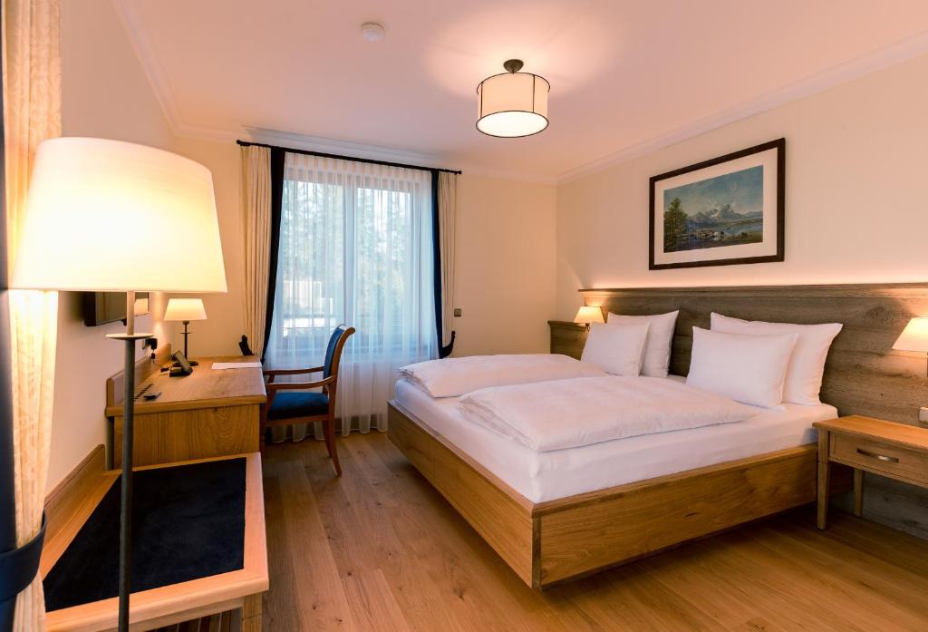 um quarto com uma cama, uma secretária e um candeeiro em Hotel & Gaststätte zum Erdinger Weißbräu em Munique