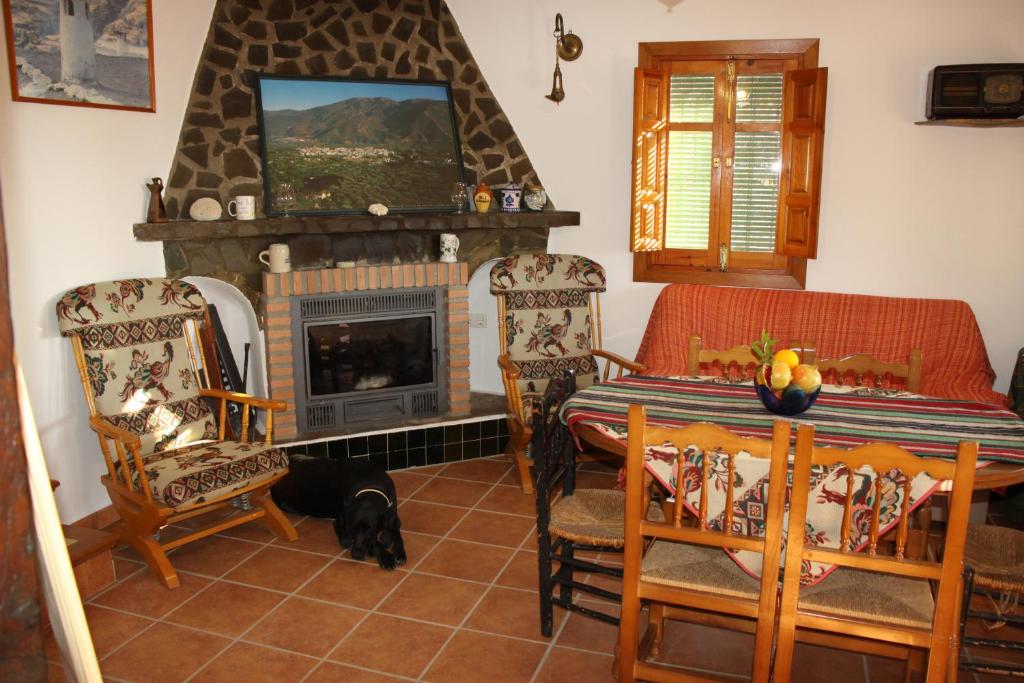 Una sala de estar con chimenea y una mesa y sillas. en Cortijo El Cerrillo, en Granada