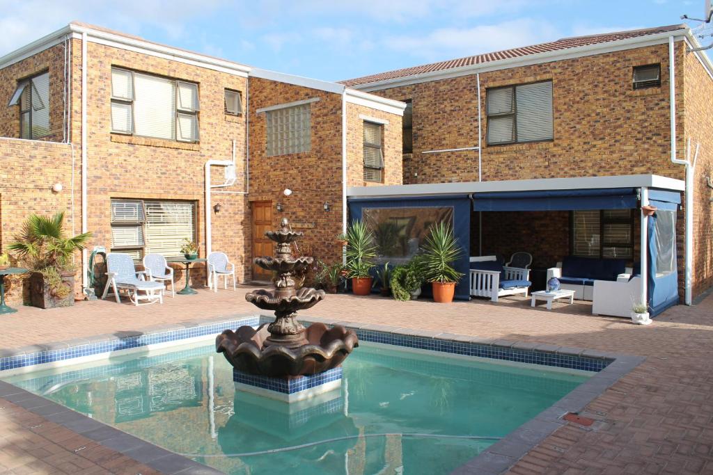 a swimming pool with a fountain in front of a building at Quest Bed And Breakfast in Melkbosstrand