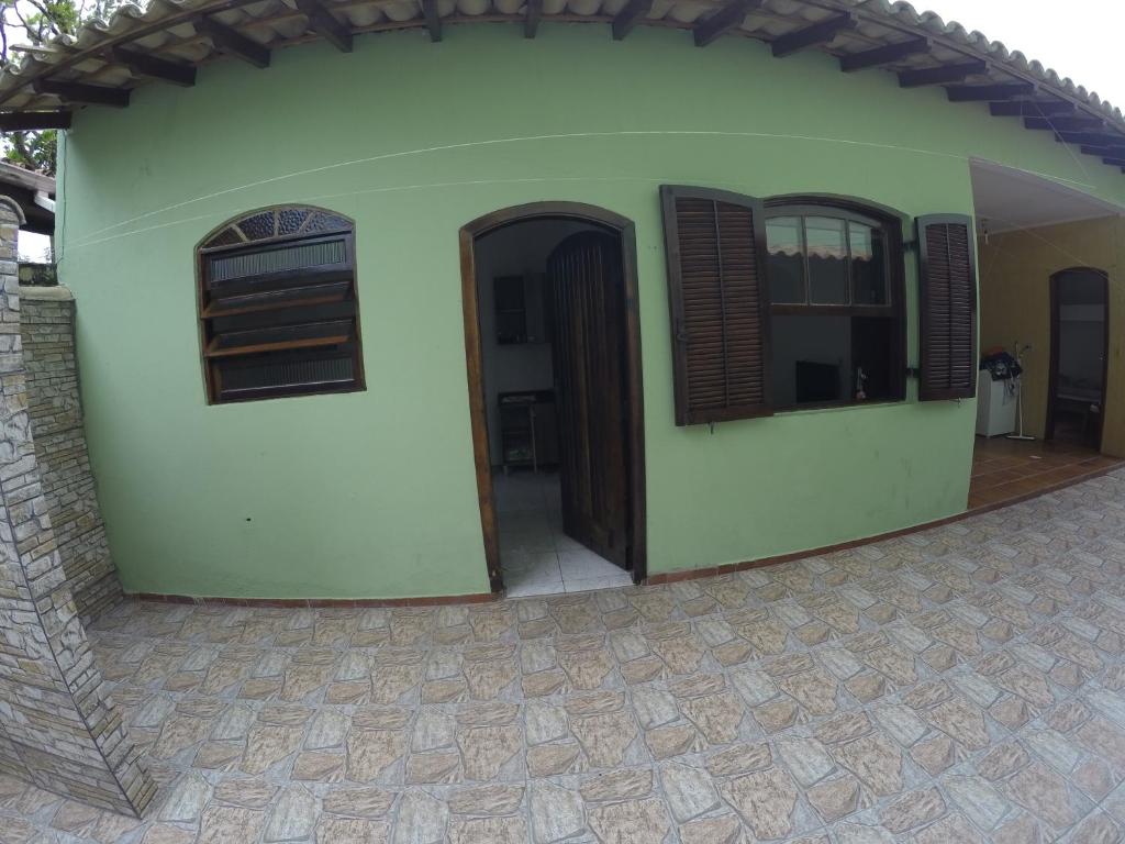 a green house with two windows and a patio at EDÍCULA 3 CÔMODOS-Enseada in Guarujá