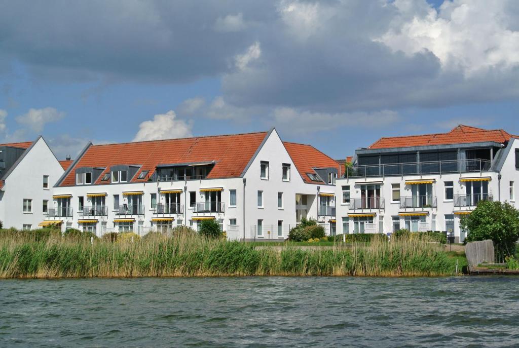 eine Reihe weißer Gebäude neben einem Wasserkörper in der Unterkunft Residenz am Seeufer in Waren (Müritz)