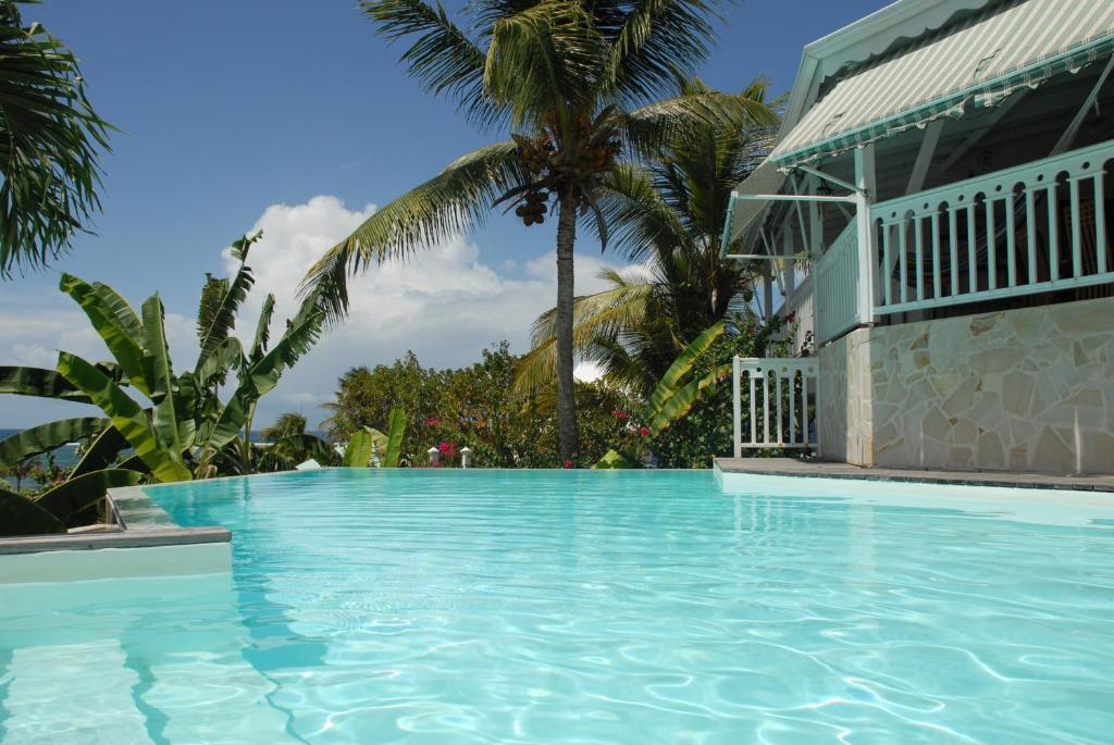 a swimming pool in front of a house with palm trees at Villa Les Nereides in Le Moule