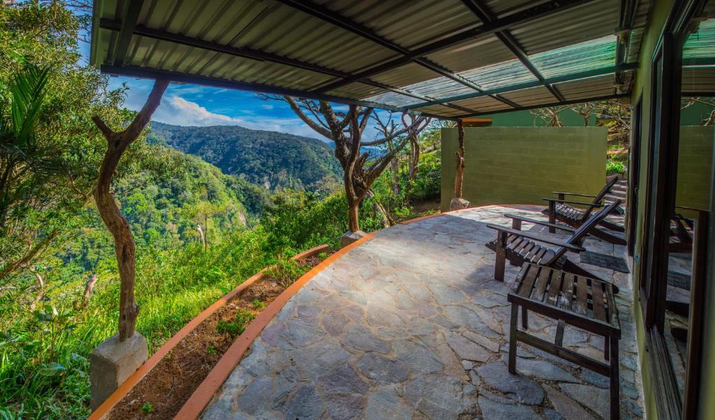 un patio con bancos y vistas a las montañas en Rainbow Valley Lodge Costa Rica en Monteverde Costa Rica