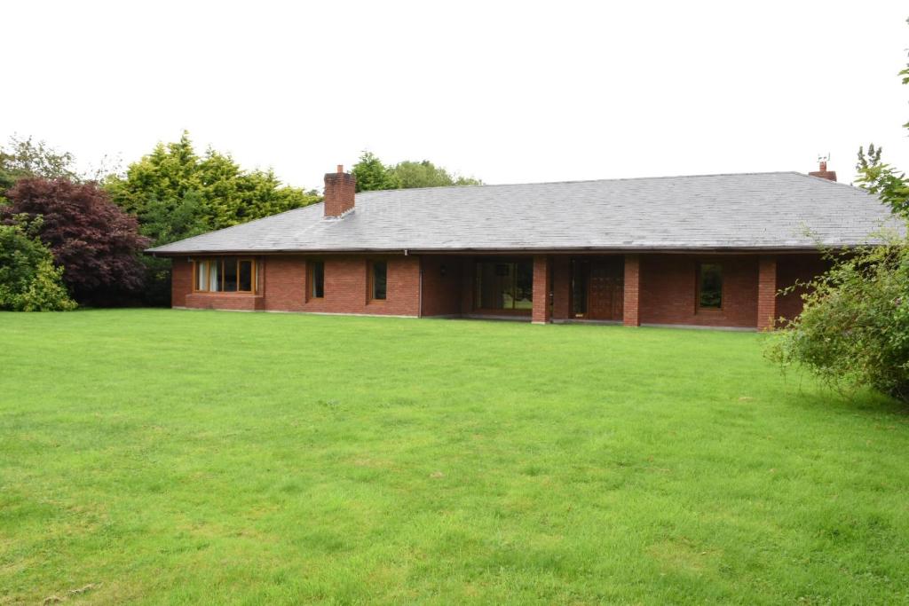 a red brick house with a large green yard at Lios Daire in Killarney