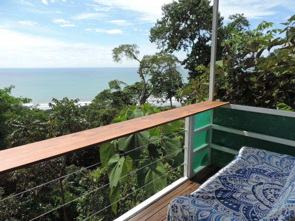 a balcony with a bench and a view of the ocean at Ranchos Remo Lodge in Uvita