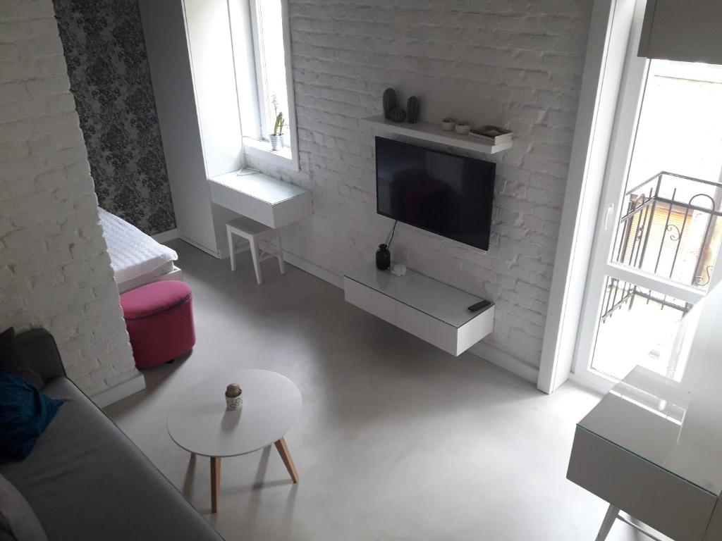 Momo Apartment في بلغراد: غرفة معيشة مع تلفزيون بشاشة مسطحة على جدار من الطوب الأبيض