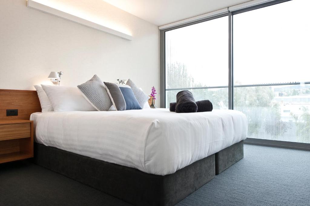 Quarry House Luxury Retreat في هوبارت: غرفة نوم بسرير كبير ونافذة كبيرة