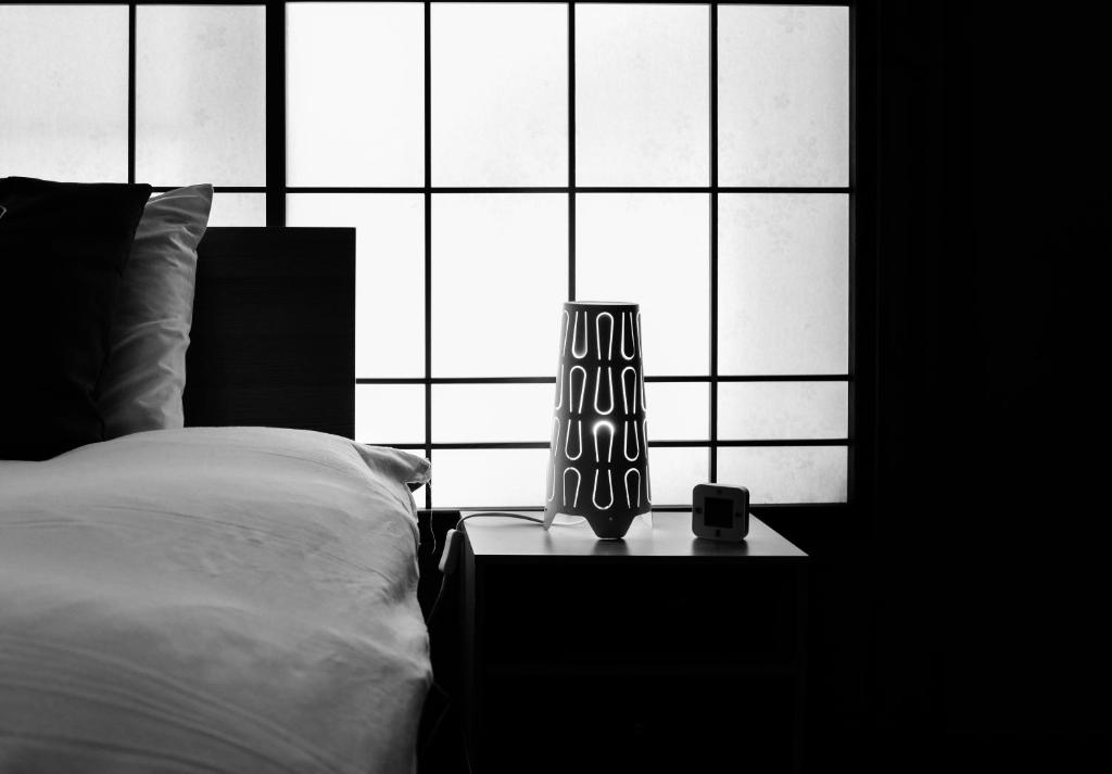 a black and white photo of a bed and a window at Sai's House Hakuba in Hakuba