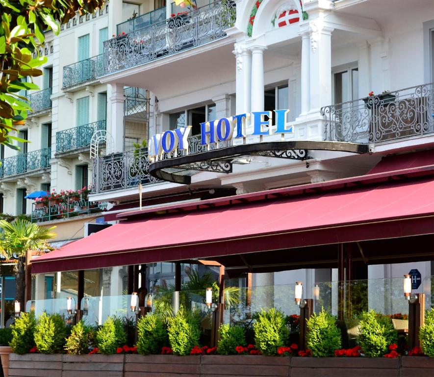 un hôtel avec un auvent rouge en face d'un bâtiment dans l'établissement Savoy Hôtel Evian, à Évian-les-Bains