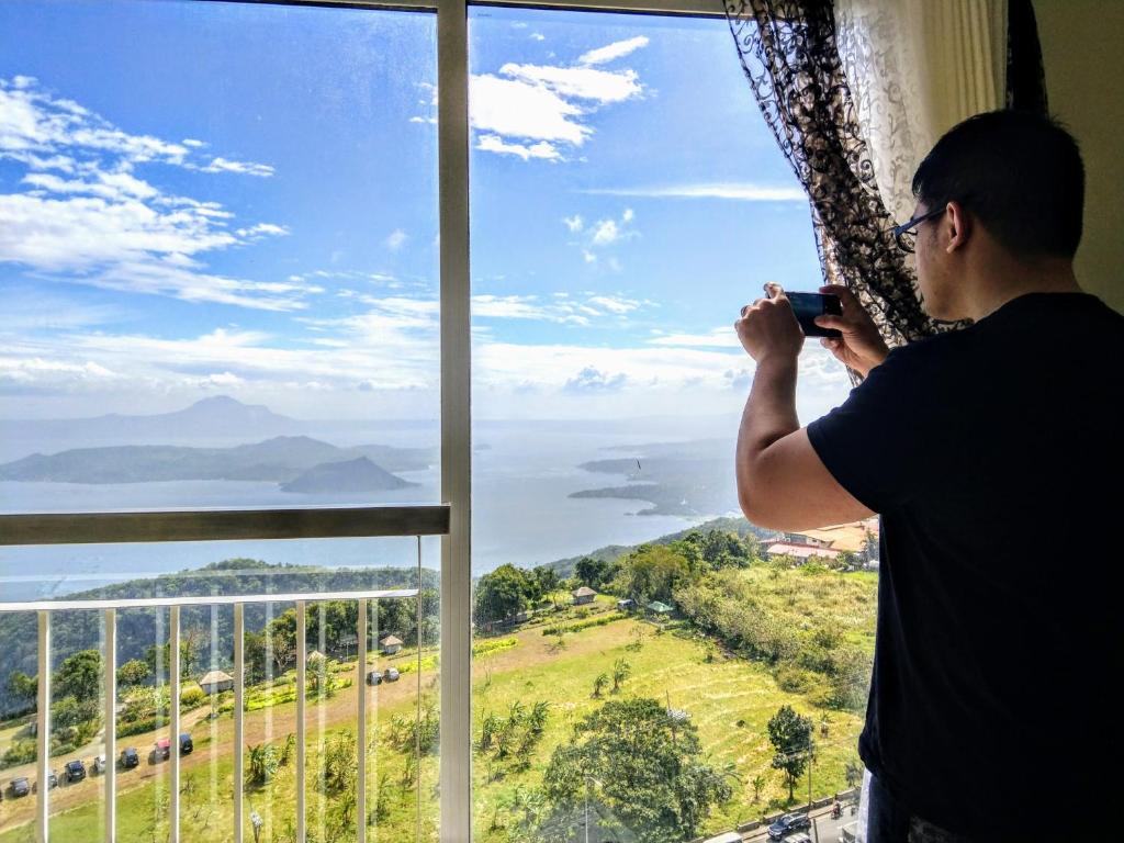 un hombre tomando una foto de la vista desde una ventana en Wind Residences For Rent - Luiice, en Tagaytay