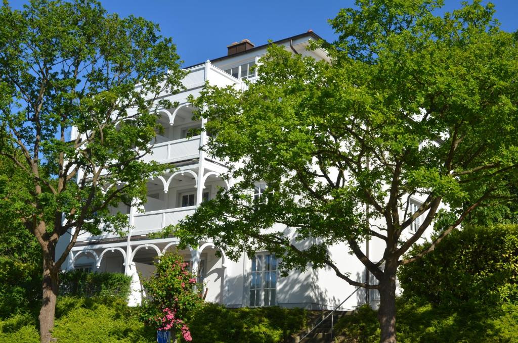 un edificio blanco con árboles delante de él en Villa Granitz - Apt. 09, en Binz