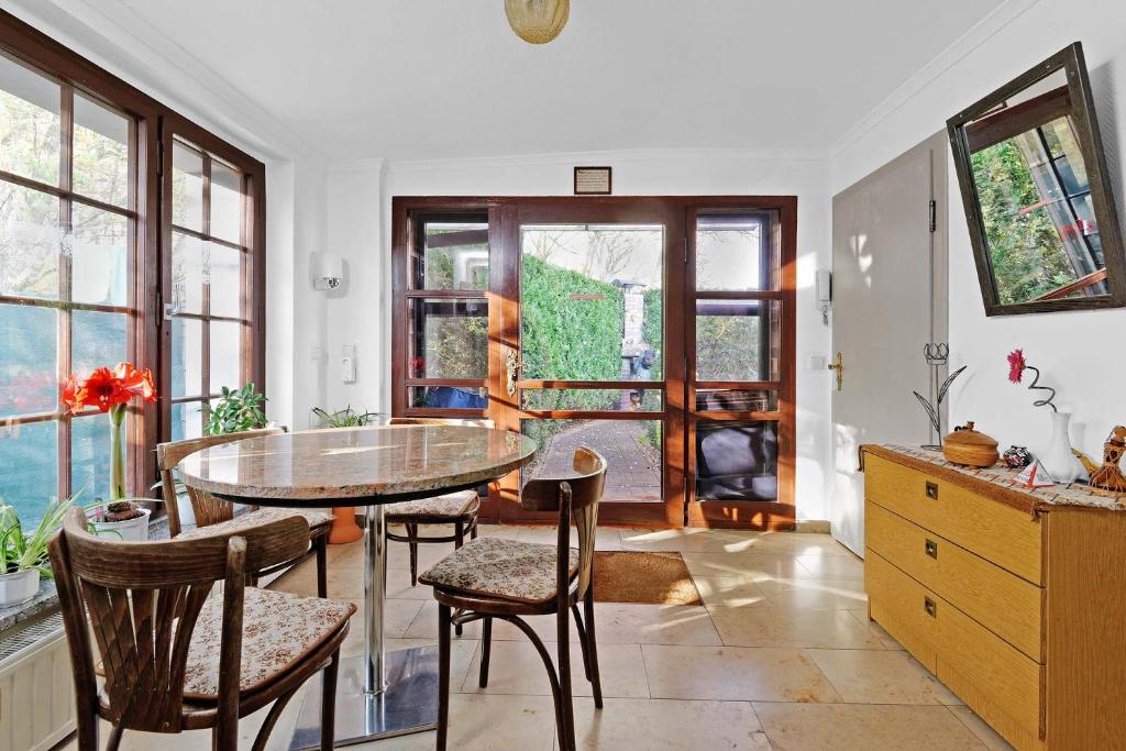 een eetkamer met een tafel, stoelen en ramen bij Cottage near centrum, paradise in Berlijn