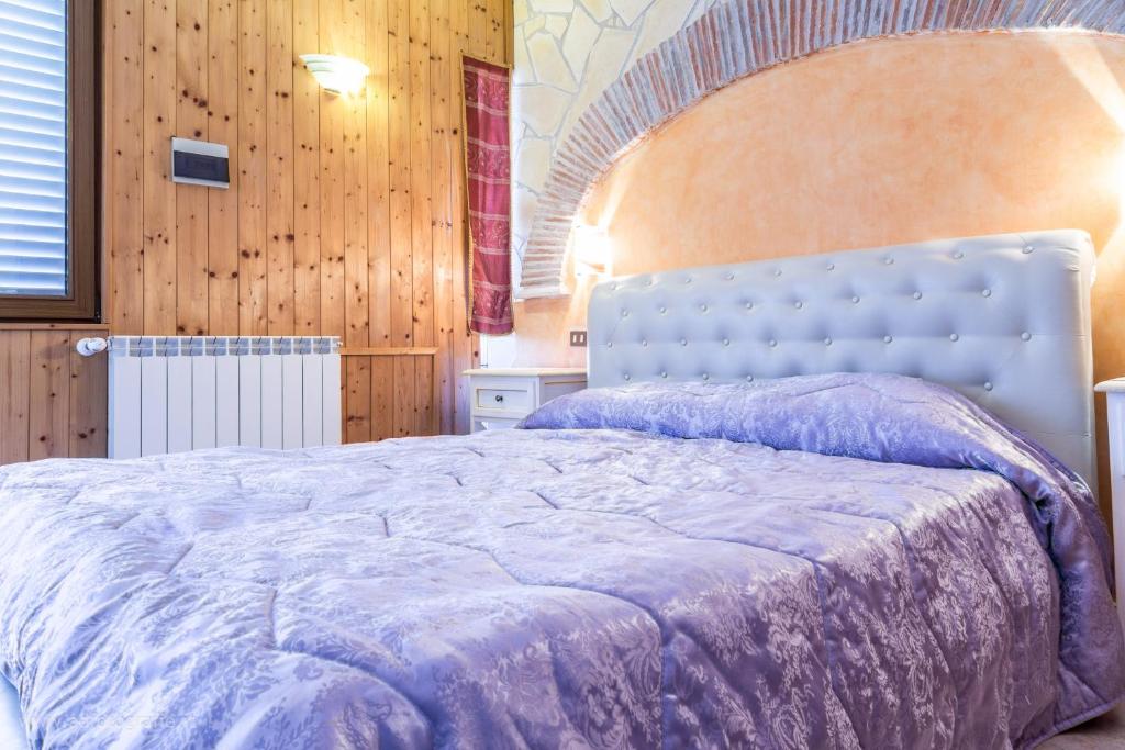 um quarto com uma cama grande e um edredão roxo em Agriturismo Le Querce em Bomarzo