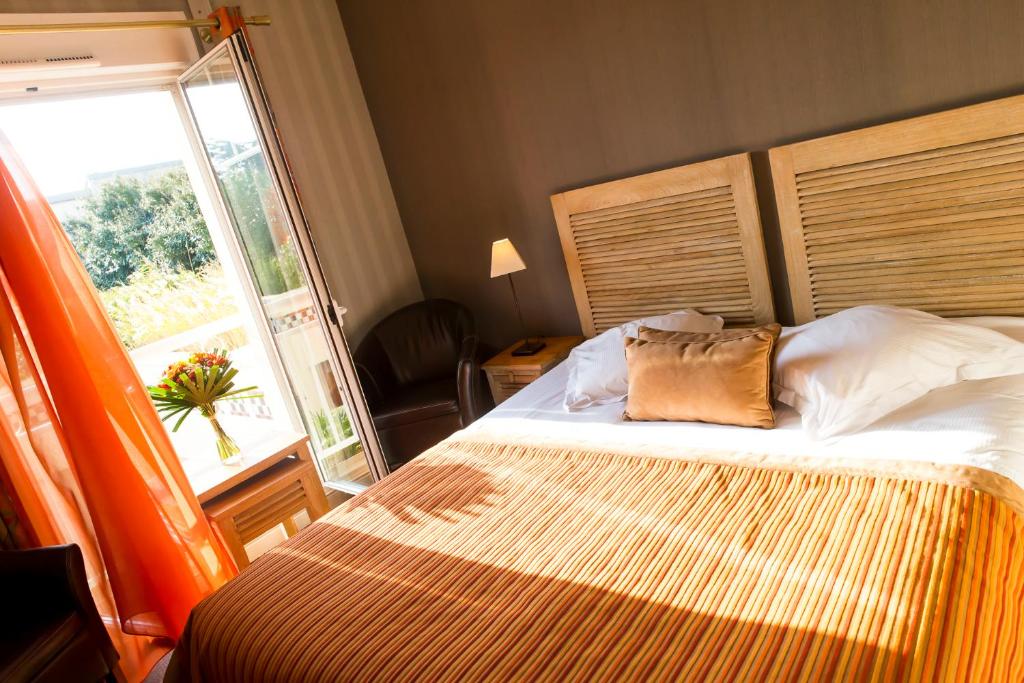 a bedroom with a bed and a large window at Almoria Hôtel & SPA in Deauville
