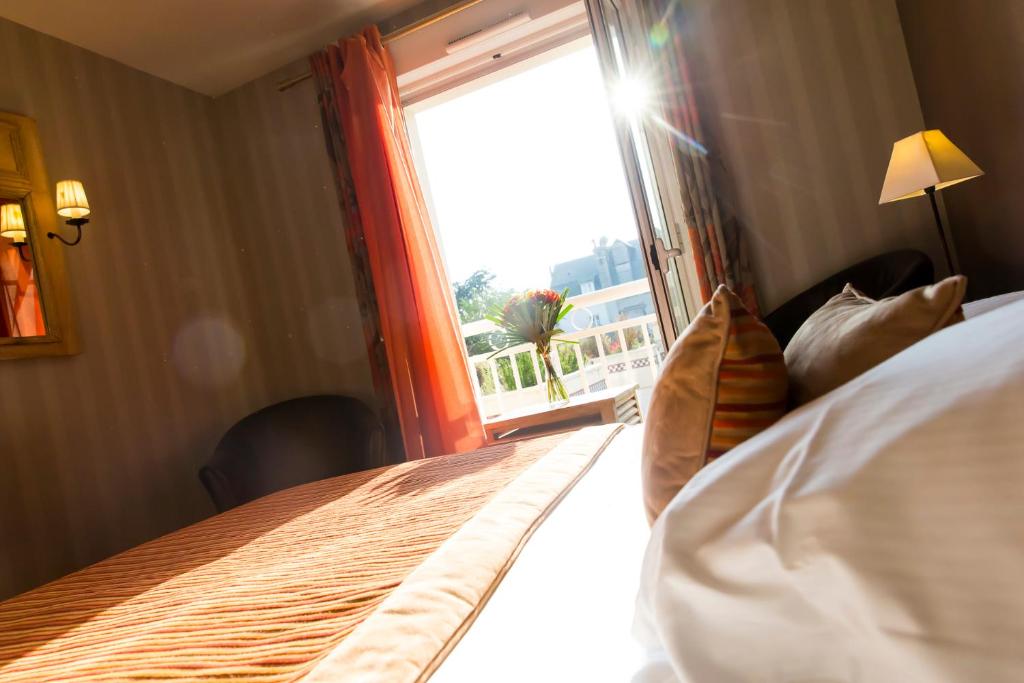 a bedroom with a large bed and a window at Almoria Hôtel & SPA in Deauville
