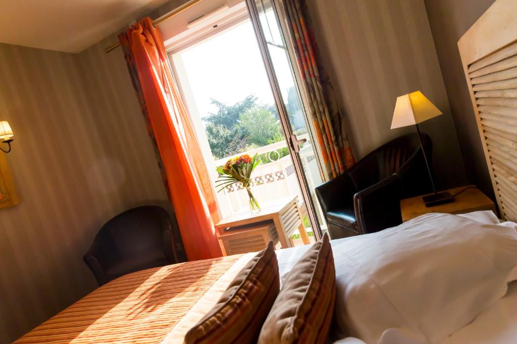 a hotel room with a bed and a window at Almoria Hôtel & SPA in Deauville