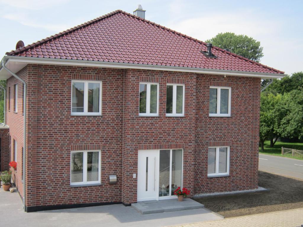 Casa de ladrillo rojo con ventanas blancas en Ferienwohnung de Jong, en Sendenhorst