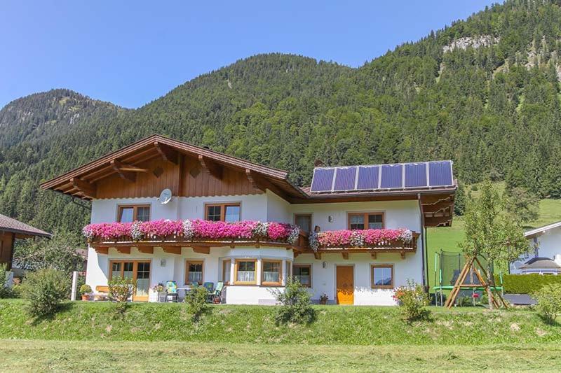 ein Haus mit Sonnenkollektoren darüber in der Unterkunft Ferienwohnung Biechl-Hauser Doris in Sankt Ulrich am Pillersee