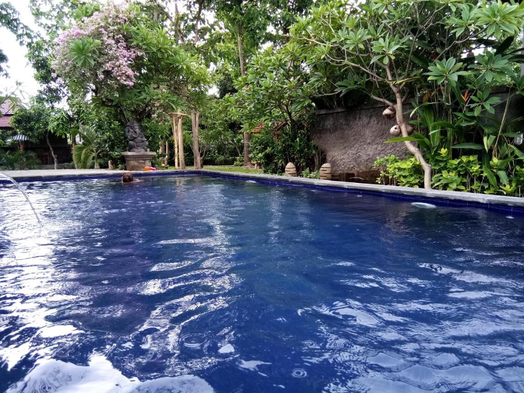 a swimming pool with blue water in a garden at Van Karning Bungalow in Pemuteran