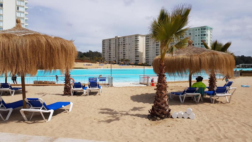 een strand met stoelen en palmbomen en een zwembad bij Laguna Bahía, Algarrobo in Algarrobo