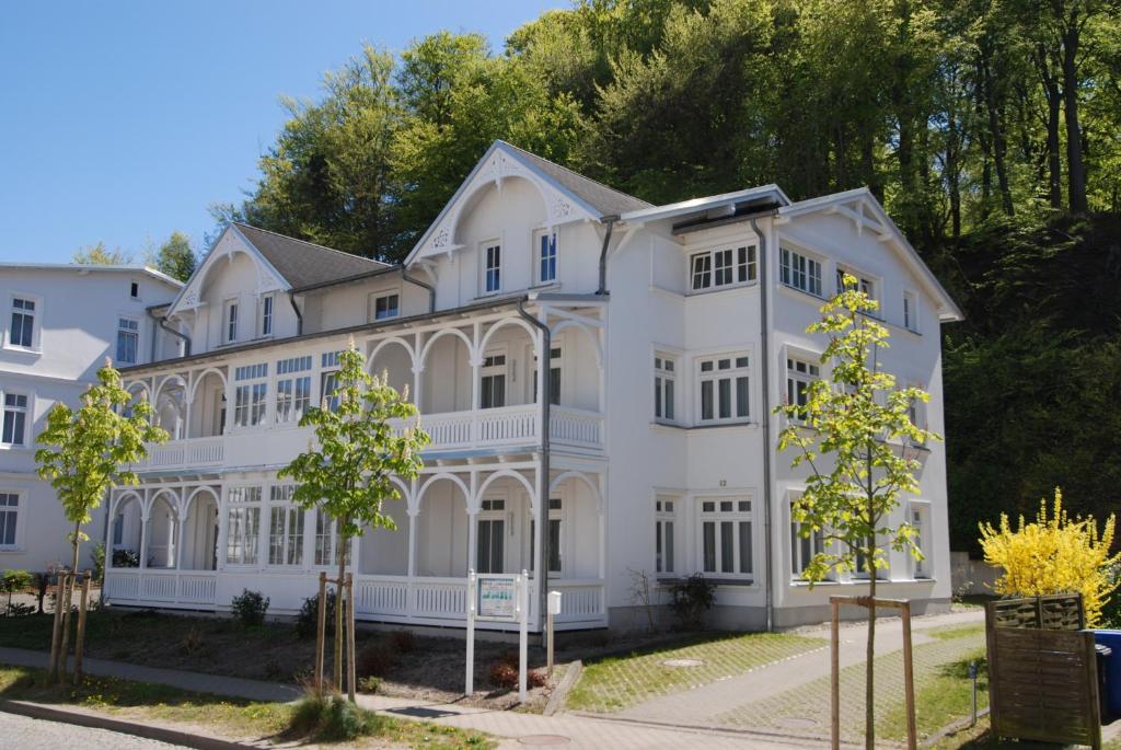 ein großes weißes Haus mit Bäumen davor in der Unterkunft OSTSEELOFT BINZ - Villa Amanda WG 08 in Binz