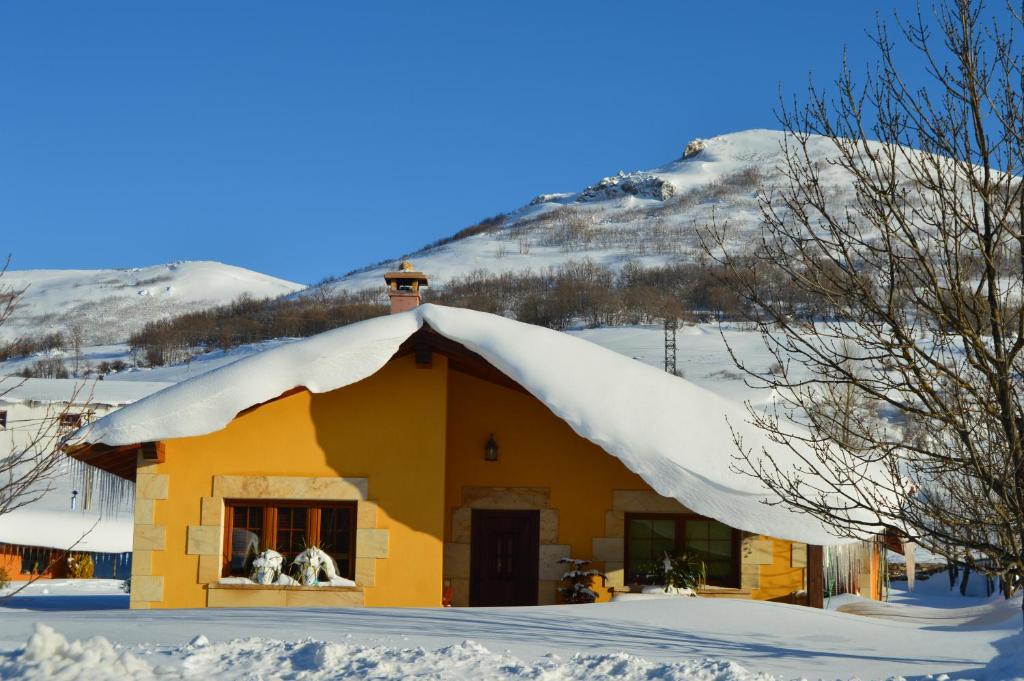 a house covered in snow with two dogs in a window at CASUCAS LA GUARIZA - Casa Susi - in Fontibre
