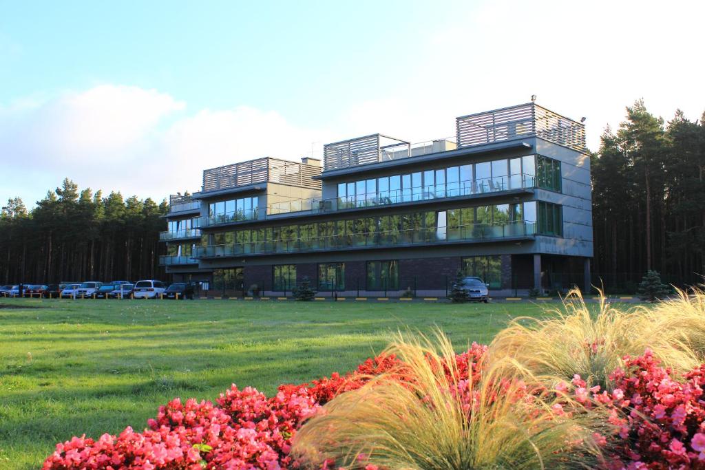 un gran edificio con un campo de flores delante de él en Meduza Hotel, en Palanga