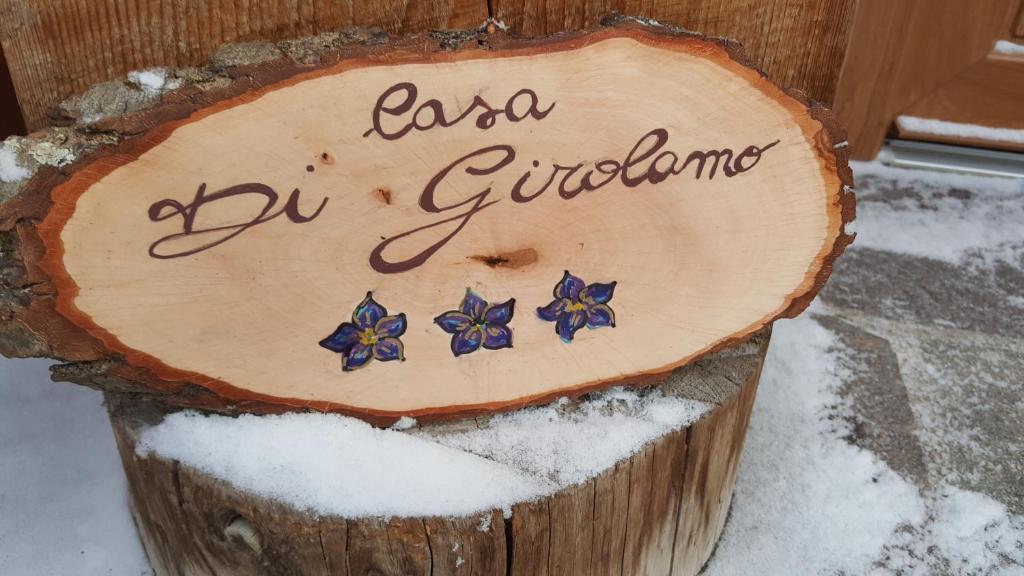 a sign on a wooden stump in the snow at Casa Di Girolamo in Predazzo
