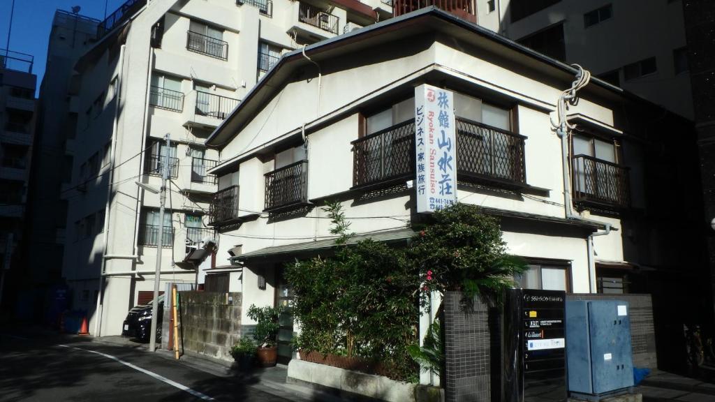 um edifício branco com um sinal na lateral em Ryokan Sansuiso em Tóquio