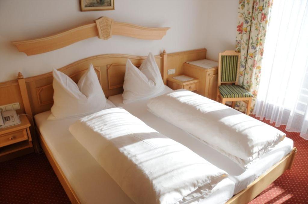 a bed with white sheets and pillows on it at Gasthof-Pension Ortner in Stadl an der Mur