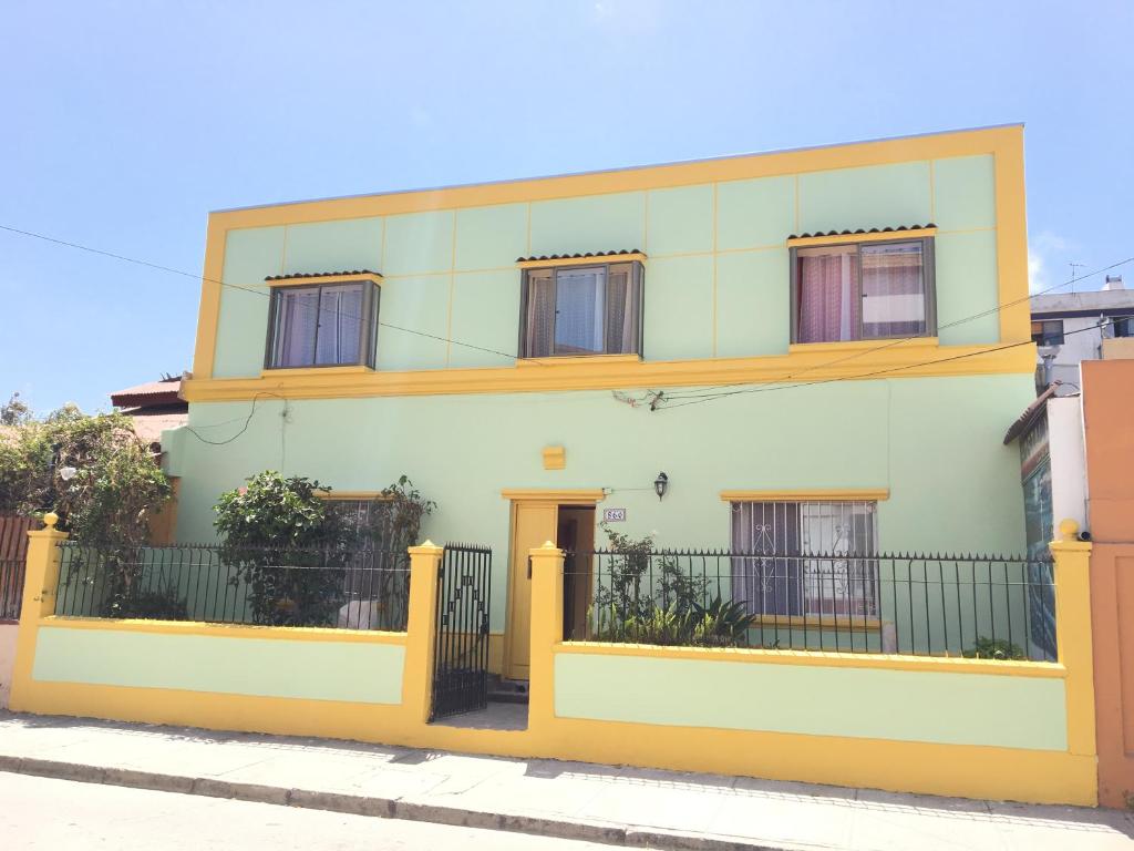 una casa amarilla y blanca con una valla en Hostal Luna del Mar, en La Serena
