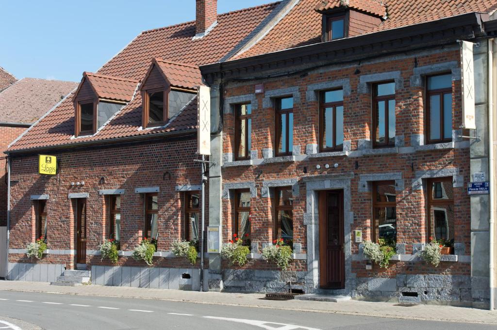 un bâtiment en briques avec des plantes en pot dans une rue dans l'établissement Auberge Le XIX eme, à Thulin