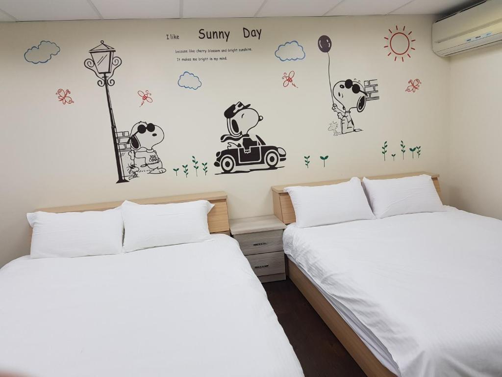 un dormitorio con 2 camas y un mural de un hombre en un coche en Fengjia Line Stack, en Taichung