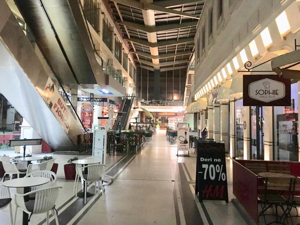 an empty shopping mall with tables and chairs in it at Rooms Dionis in Tirana