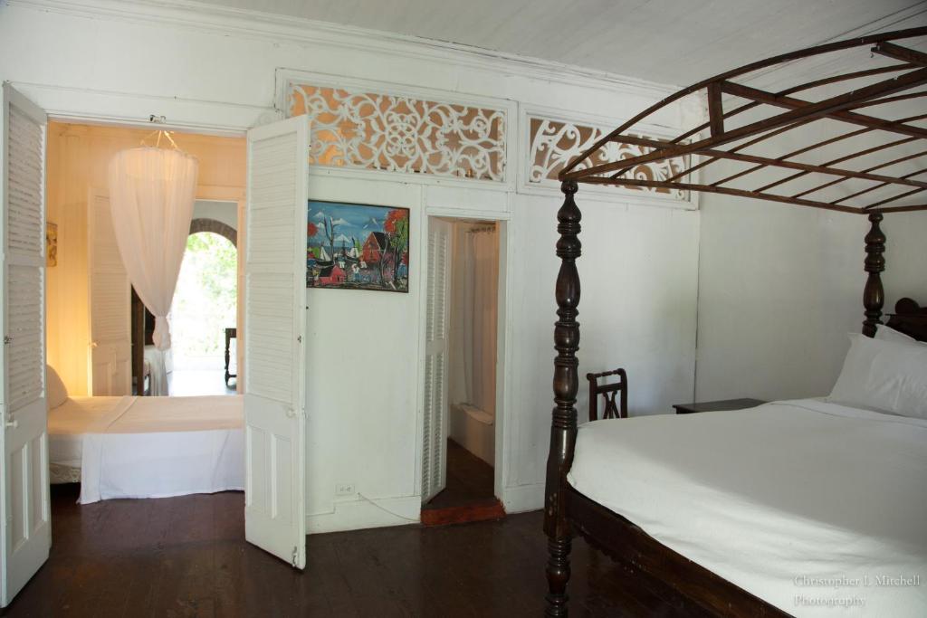 
a bedroom with a white bed and white walls at Hotel Florita Residential Hotel in Jacmel
