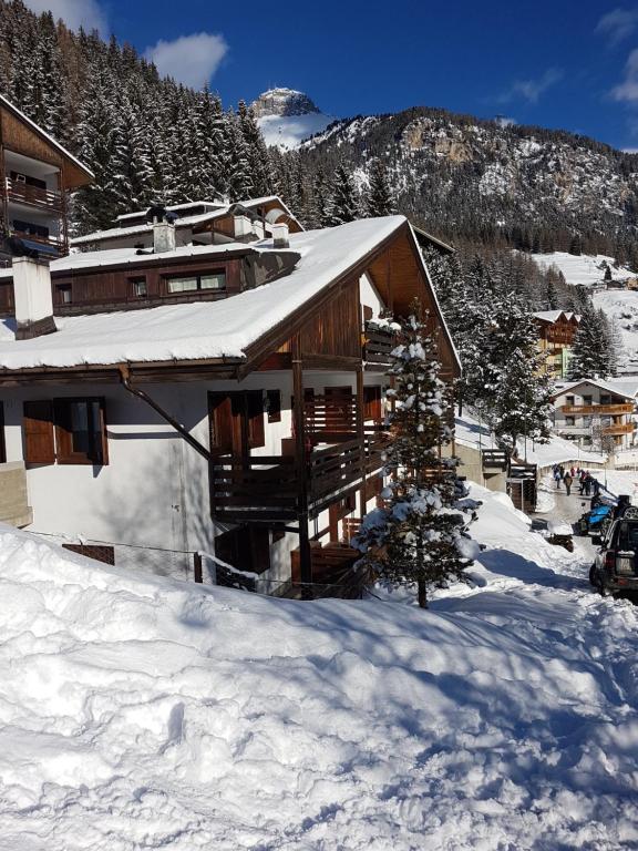 a ski lodge in the snow in front of a mountain at Appartamento panoramico Campitello di Fassa in Campitello di Fassa