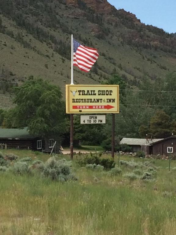 una señal para una tienda de trenes con bandera americana en Trail Shop Inn, en Wapiti