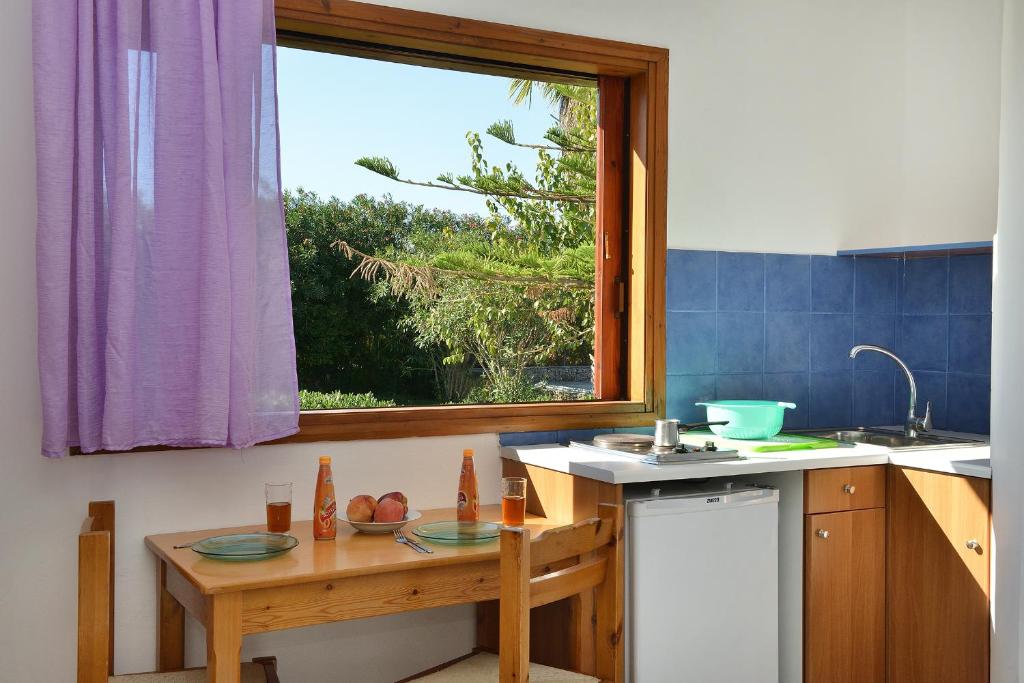 una cocina con una mesa pequeña y una ventana en San Antonio Apartments en Kolymvari